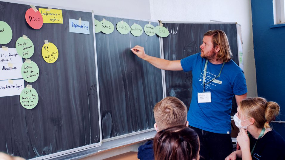 plenergy Moderator und Schüler vor Tafel