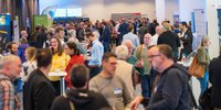 Ein Raum mit ca. 250 Menschen, leicht von oben fotografiertm zeigt die Ausstellung von Thüringer Firmen auf dem ThEGA-Forum 2024