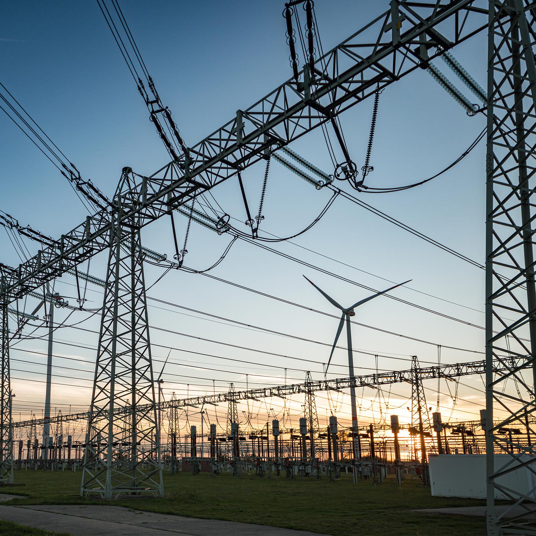 Hochspannungsleitungen und Windräder Hochspannungsleitungen und Windenergieanlagen vor einem Sonnenuntergang
