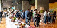 Pausesituation bei der REKON 2025 in der Weimarhalle, es ist eine Tafel mit weißer Tischdecke zu sehen auf der kleine Snacks aufgestellt wurden. Menschengruppen stehen vereinzelt in der Nähe. 