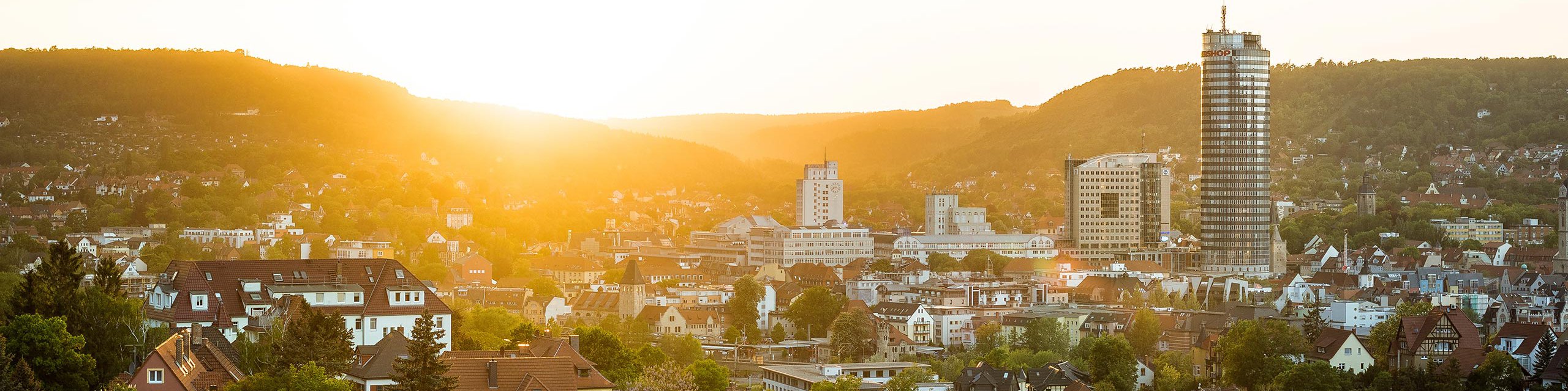 Blick auf die Thüringer Stadt Jena vor einem Sonnenuntergang und mit den Kernbergen im Hintergrund