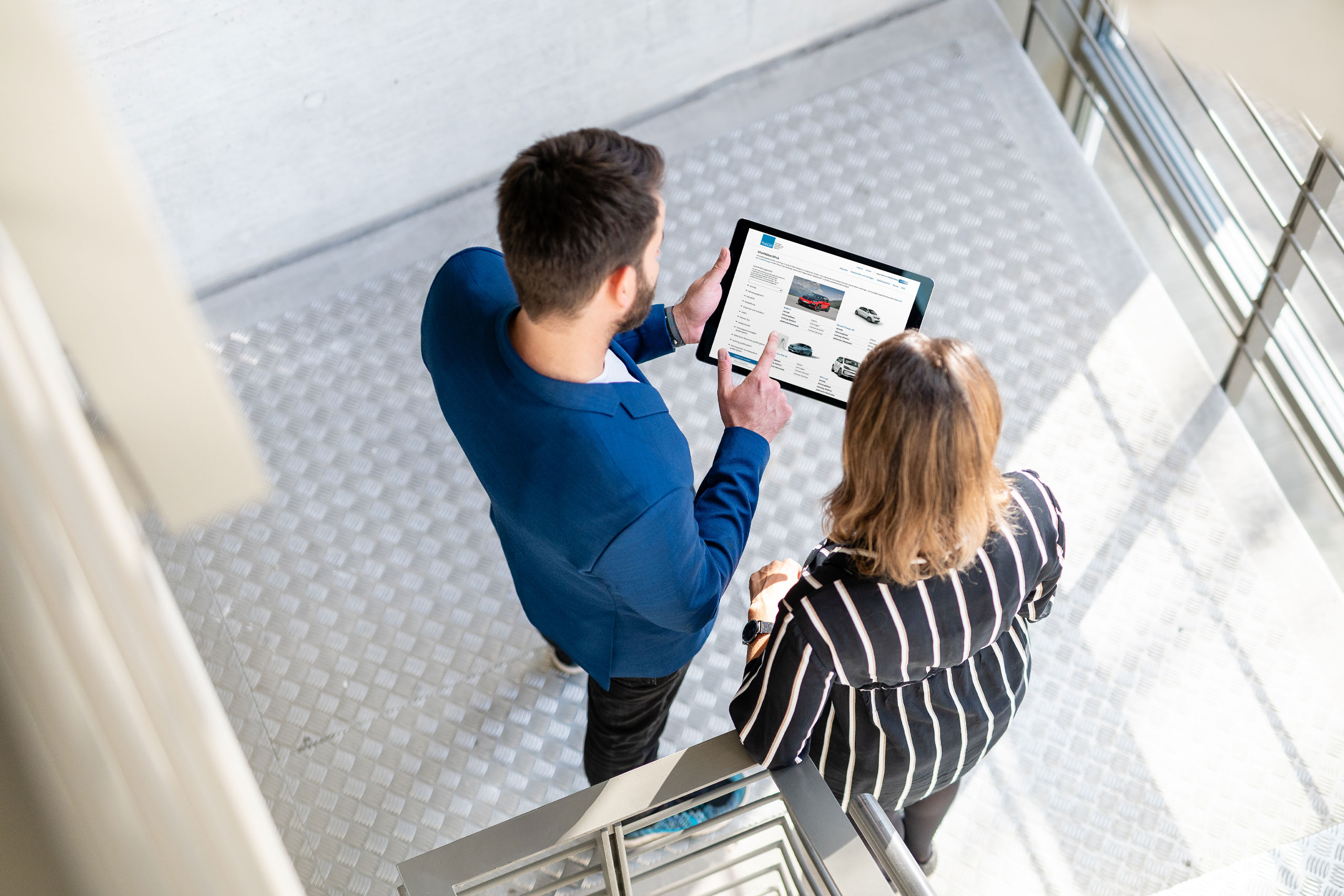 Ein Mann und eine Frau schauen auf ein Tablet mit dem Mobilitätskompass auf dem Bildschirm