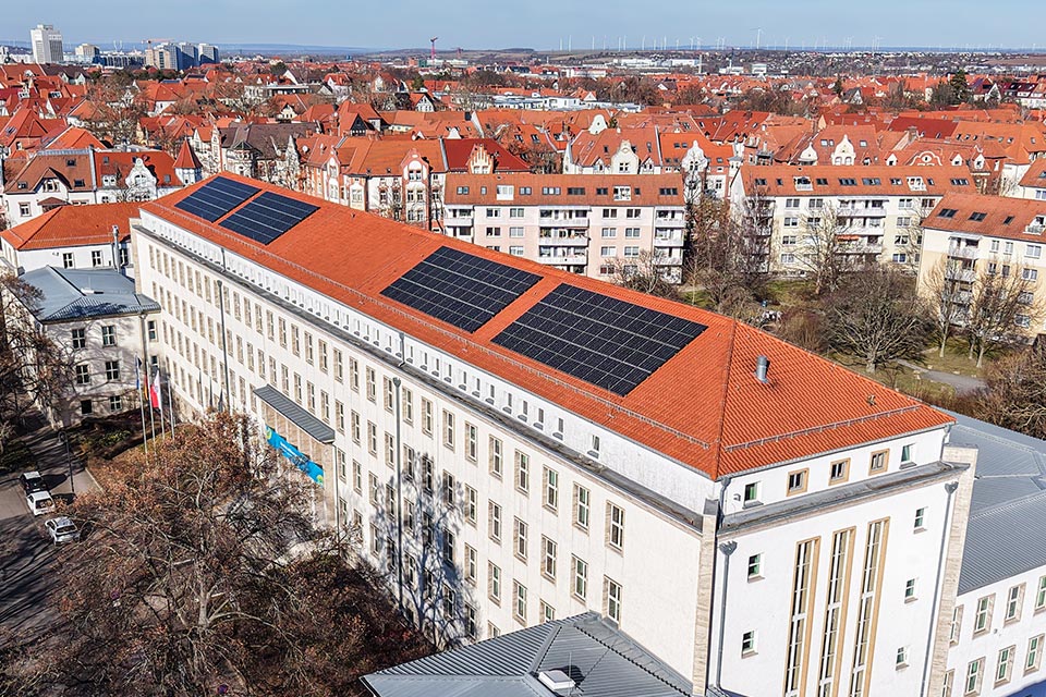Blick von oben auf die Solaranlage auf dem Dach des Thüringer Umweltministeriums und die Stadt Erfurt im Hintergrund