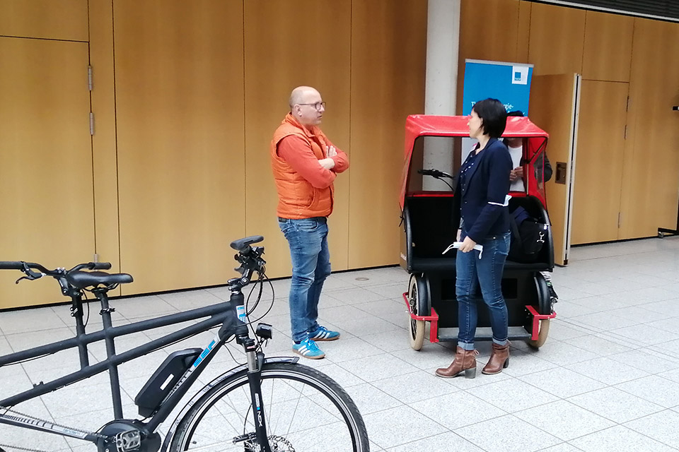 Zwei Thüringer E-Lotsen testen während einer Tagungspause eine Fahrrad-Rikscha