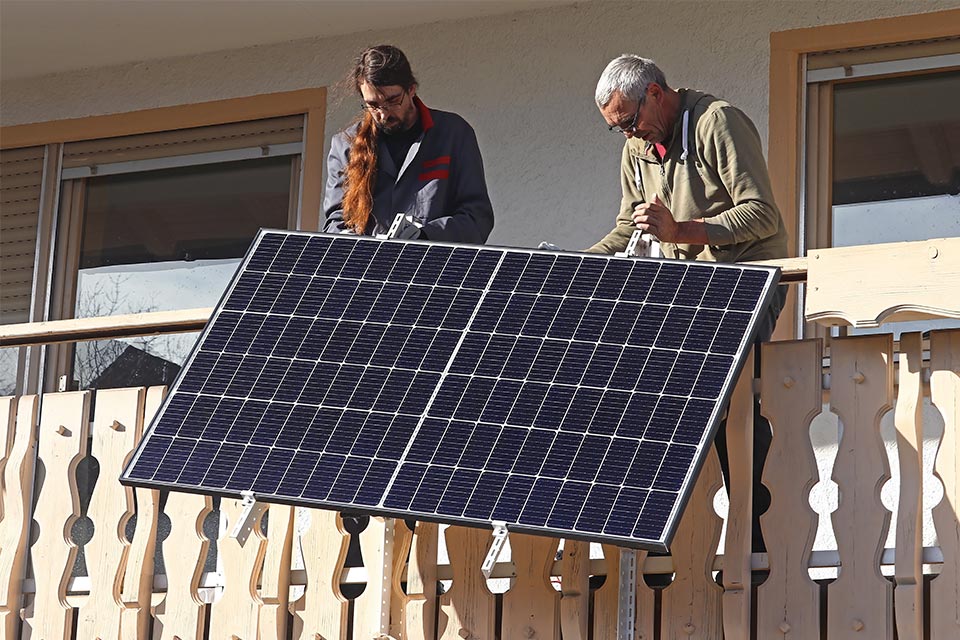 Zwei Maenner montieren Solaranlage an Balkon