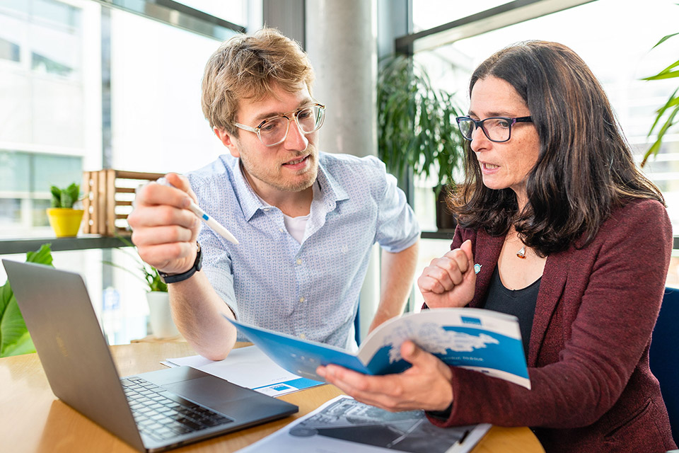 Mann und Frau sitzen vor Laptop und führen ein Beratungsgespräch