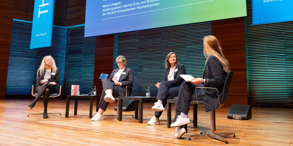 Podiumsdiskussion auf der REKON 2025 in der Weimarhalle Podiumsdiskussion auf der REKON 2025 in der Weimarhalle, mit Caro Matzko als Moderatorin und drei weiteren Rednerinnen. Alle sitzen auf Stühlen