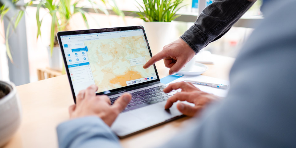 Energieatlas Thüringen der Landesenergieagentur (ThEGA) wird erklärt Mann sitzt vor einem Laptop und bekommt von einer anderen Person den Energieatlas der Landesenergieagentur Thüringen (ThEGA) erklärt
